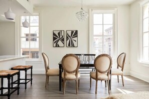 Enjoy meals in this stylish dining area with a black table and four classic chairs, surrounded by abstract art and natural light.