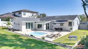 Une maison moderne à deux étages, dotée d’une piscine, de mobilier de jardin et d’une cour arrière clôturée.