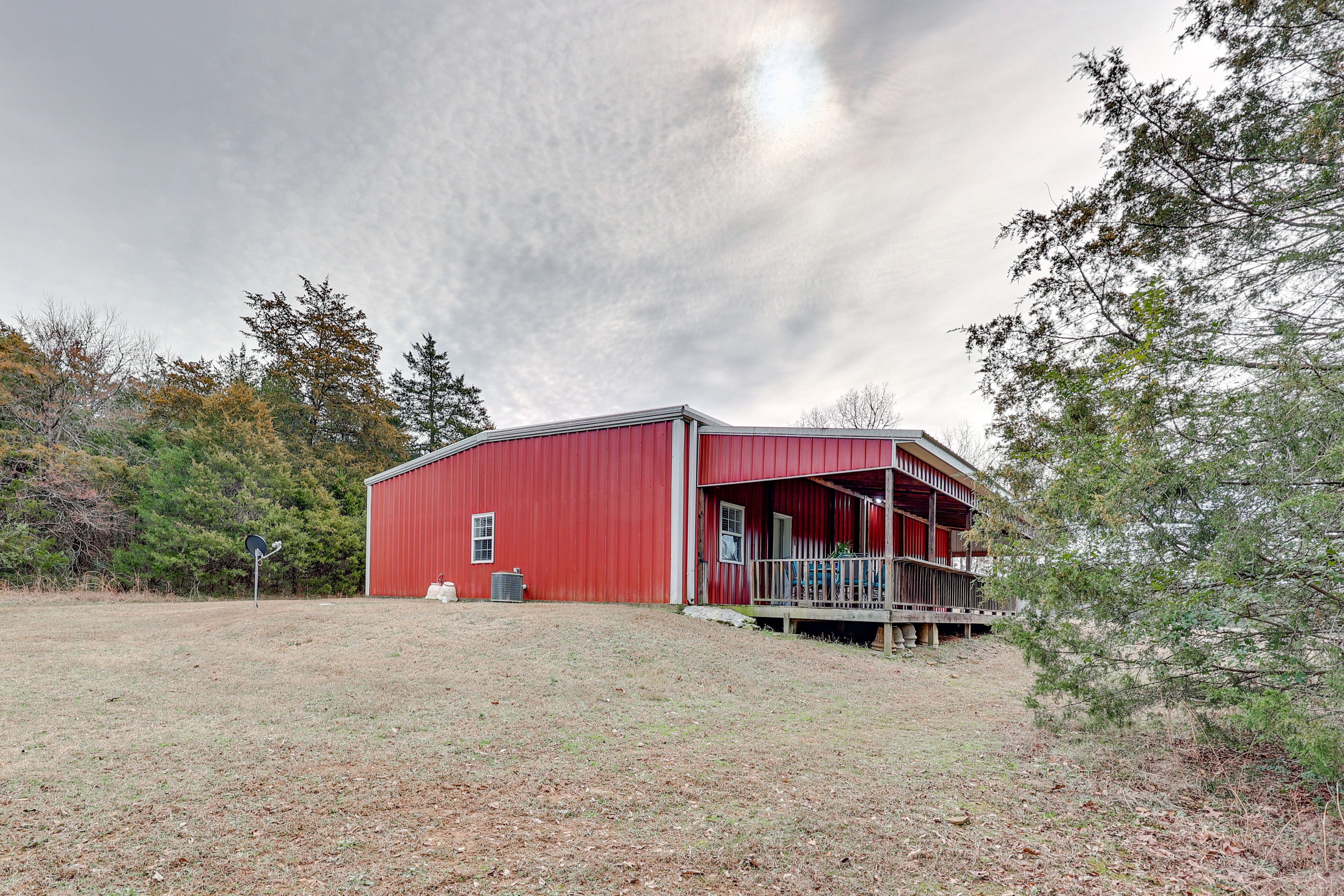 A red barn with a porch and a grassy yard.
