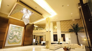 A spacious lobby with a high ceiling, a large decorative wall piece, and a reception desk. - Godwin Meerut (Meerut)
