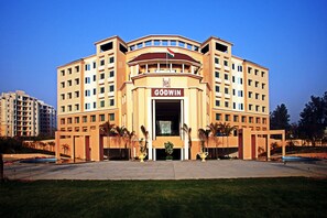 A multi-story hotel with a prominent entrance, a flag, and a name sign.