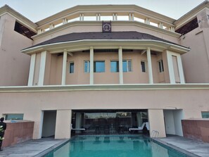 A large building with a pool, multiple windows, and a balcony.