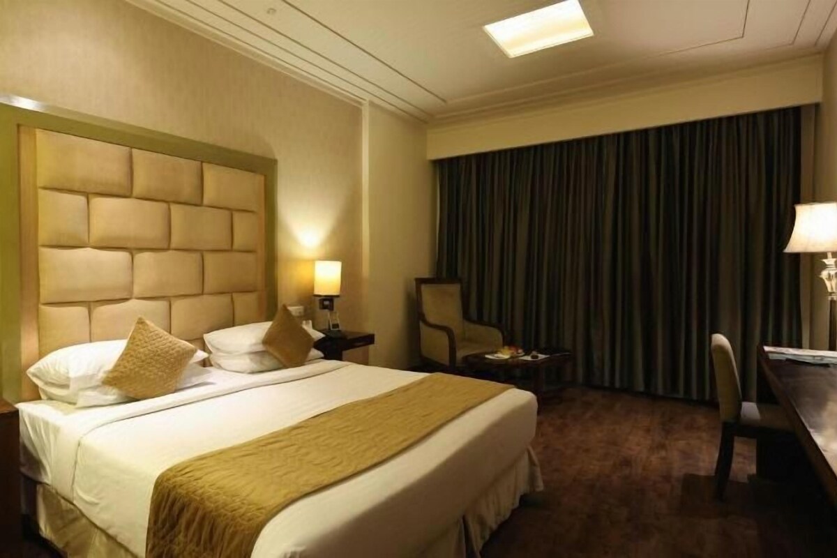 Une chambre d’hôtel avec un grand lit, des tables de chevet, des lampes, un bureau et une chaise.