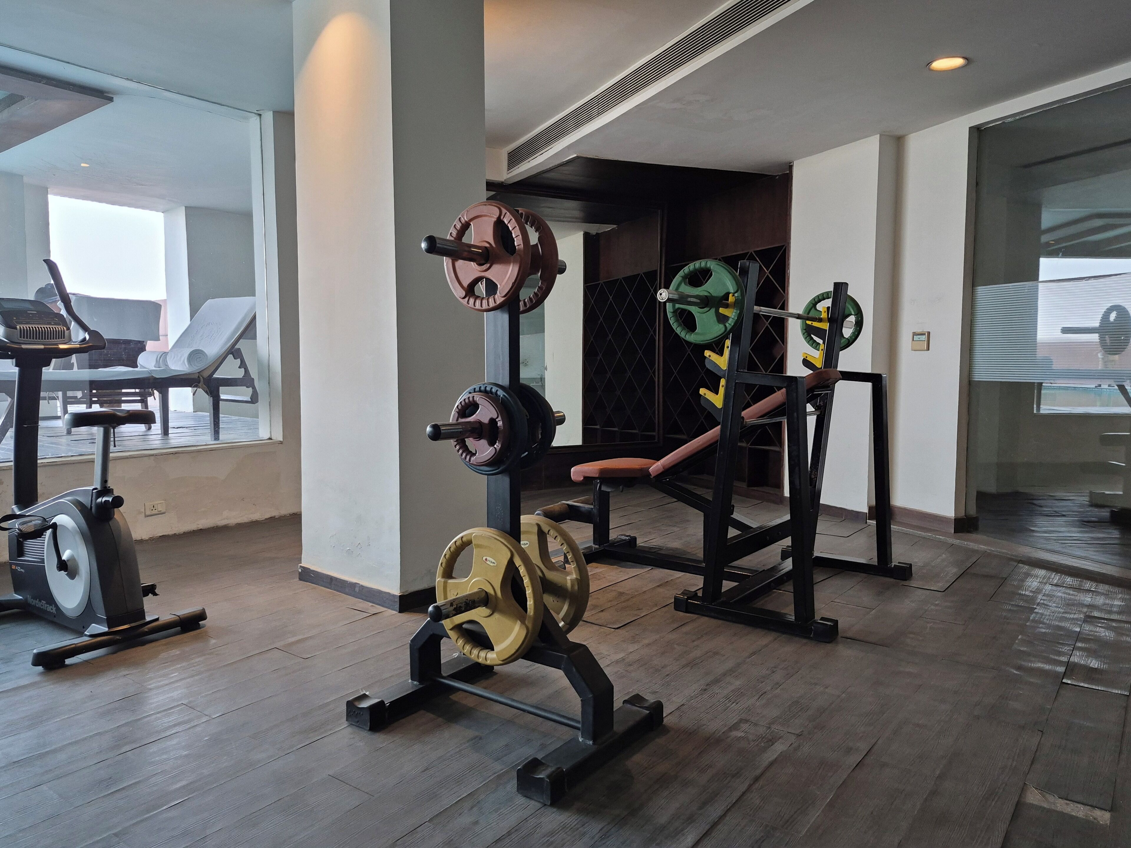 Un gimnasio con equipamiento de levantamiento de pesas, bicicletas estáticas y una banca.