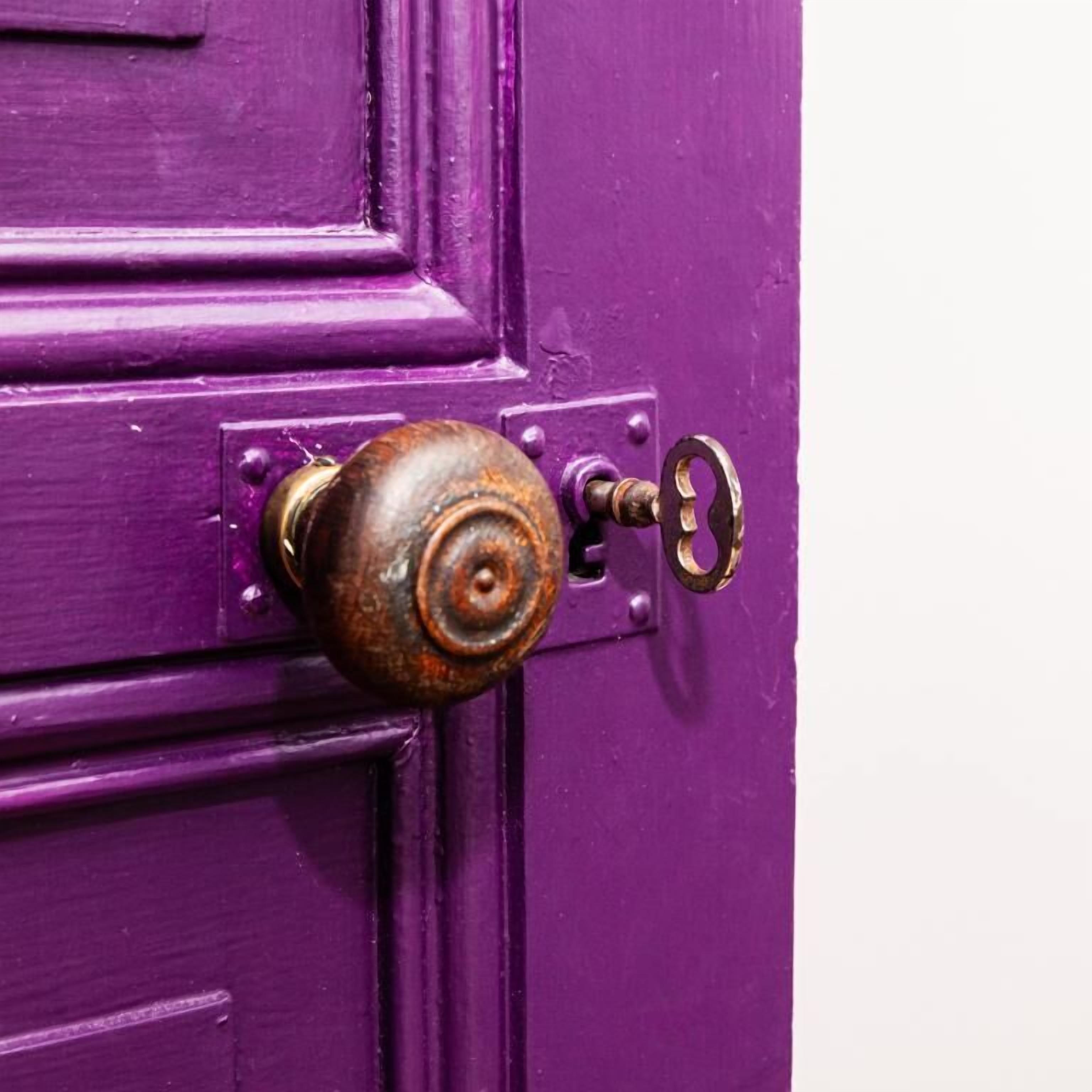 A purple door with a rusted round keyhole and a key.