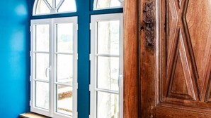 A room with two arched windows and a wooden door with a geometric pattern.