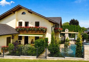 A two-story house with a balcony, a swimming pool, and a garden.