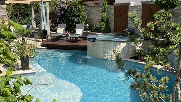 Ein Swimmingpool mit Whirlpool, Liegestühlen und einer Pergola.