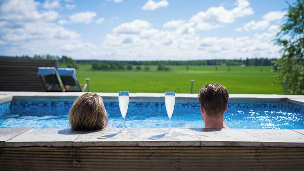 Una piscina con dos copas de champán y una tumbona.