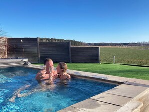 Una piscina con un pontile in legno e uno spazio verde sullo sfondo.