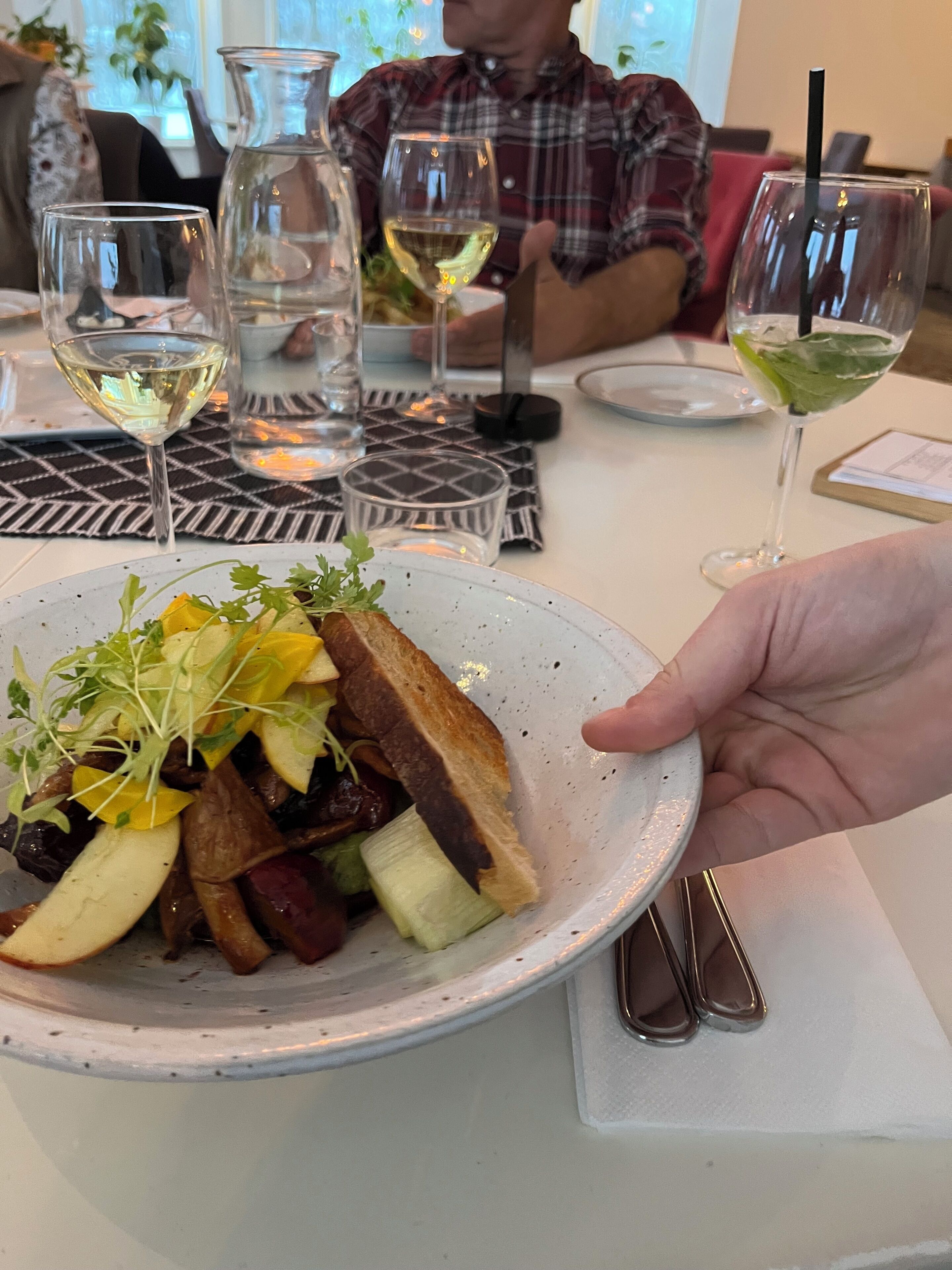 En tallrik med mat, bestående av olika sorters grönsaker och en bit bröd, som hålls i en hand.