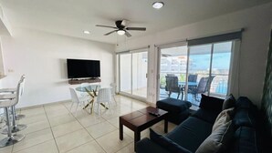 A modern living room with a sofa, coffee table, TV, and a balcony with outdoor furniture. - Beautiful in marina, amazing views by Gpsrentas (Mazatlán)