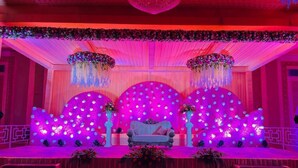 A stage with a sofa, floral arrangements, and a backdrop with hanging lights. - Vrindavan Resort (Mathura)