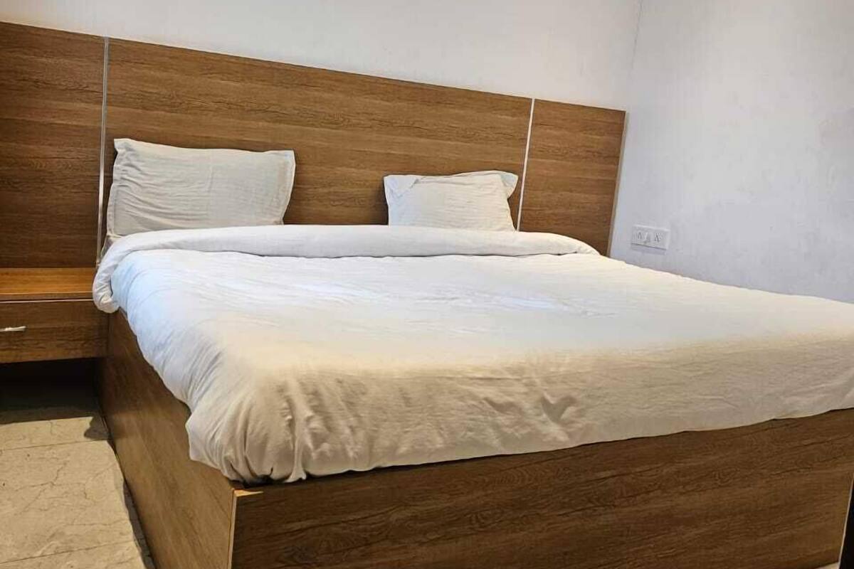 Une chambre à coucher moderne avec une tête de lit en bois, un grand lit avec une literie blanche et une table de chevet.