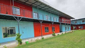 A row of colorful buildings with a flat roof and a grassy area in front. - Vrindavan Resort (Mathura)