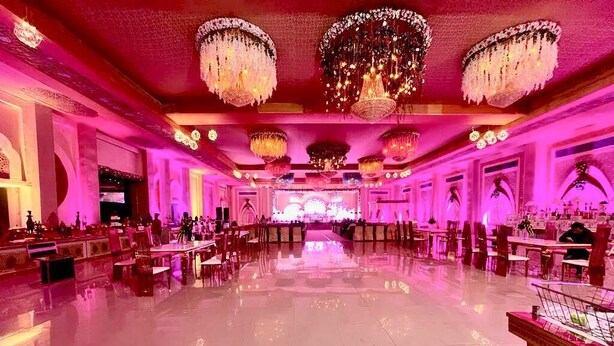 A spacious hall with chandeliers, tables, and chairs arranged for an event. - Vrindavan Resort (Mathura)