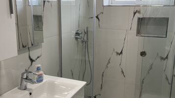 Deluxe studio | Badkamer | Een haardroger, pantoffels, handdoeken, toiletpapier