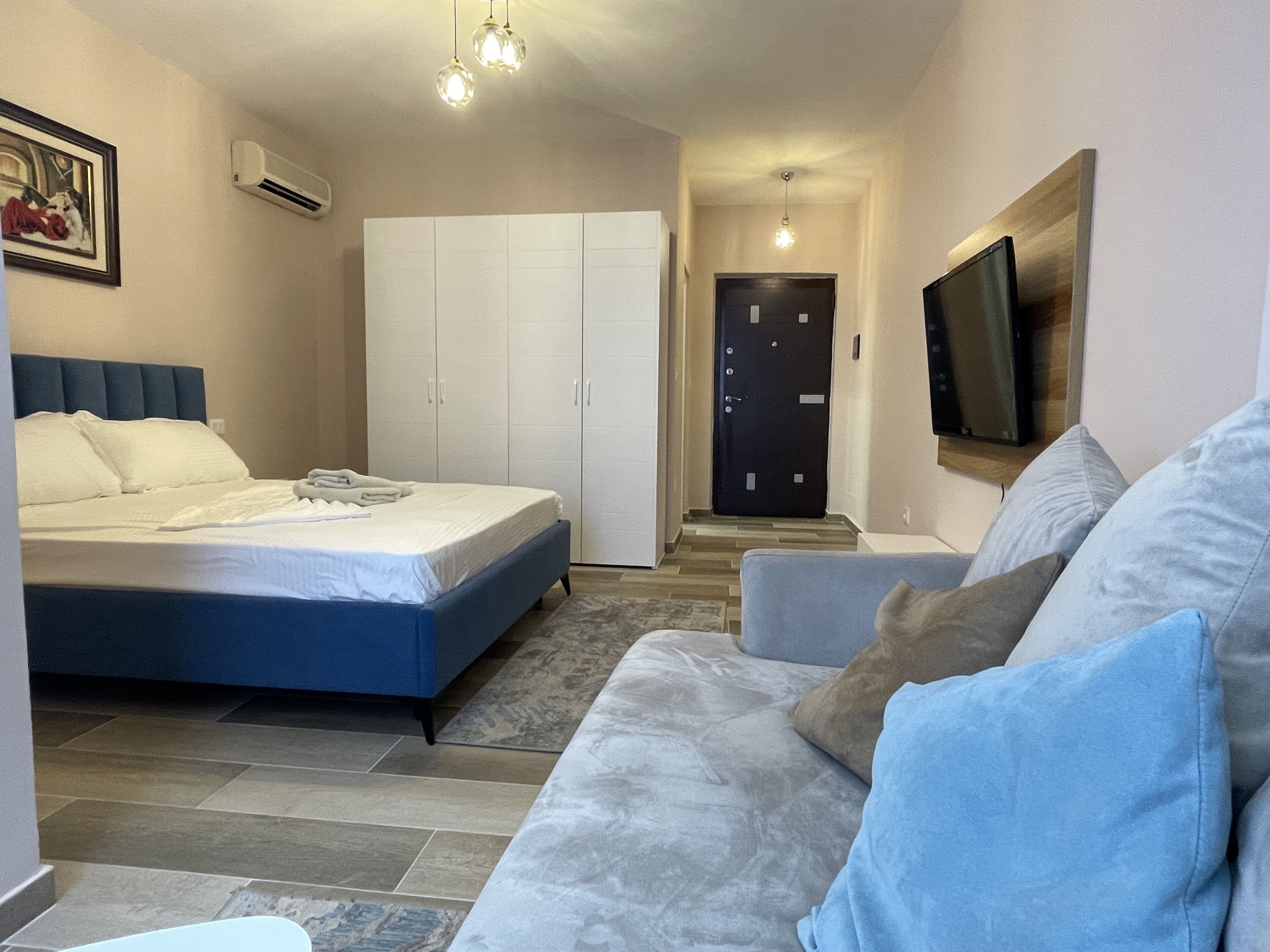 A bedroom with a bed, a wardrobe, a television, and a sofa.