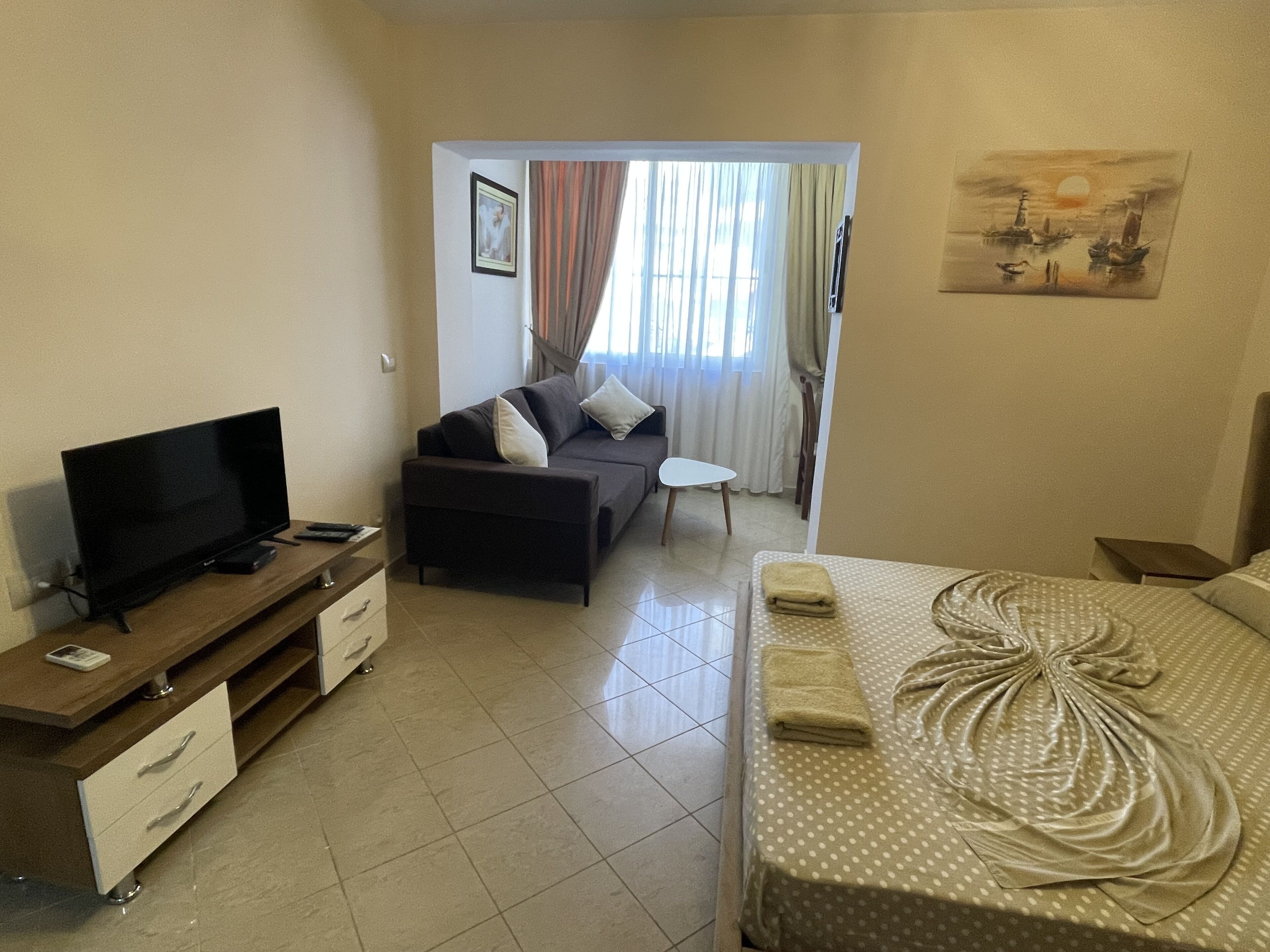 A hotel room with a bed, a TV, a sofa, and a small table.
