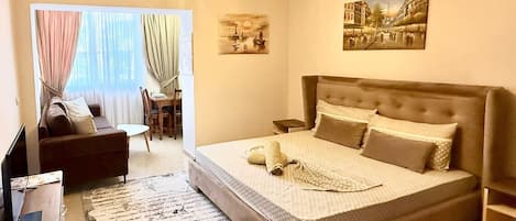 Un dormitorio con una cama grande, un sofá, un escritorio y un televisor.