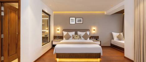A modern hotel room with a large bed, bedside tables, a mirror, and a small seating area.