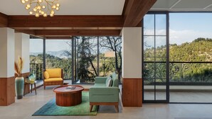 Un espacio habitable amplio con un ventanal grande, un sofá verde, un sillón amarillo y una mesa de centro de madera.