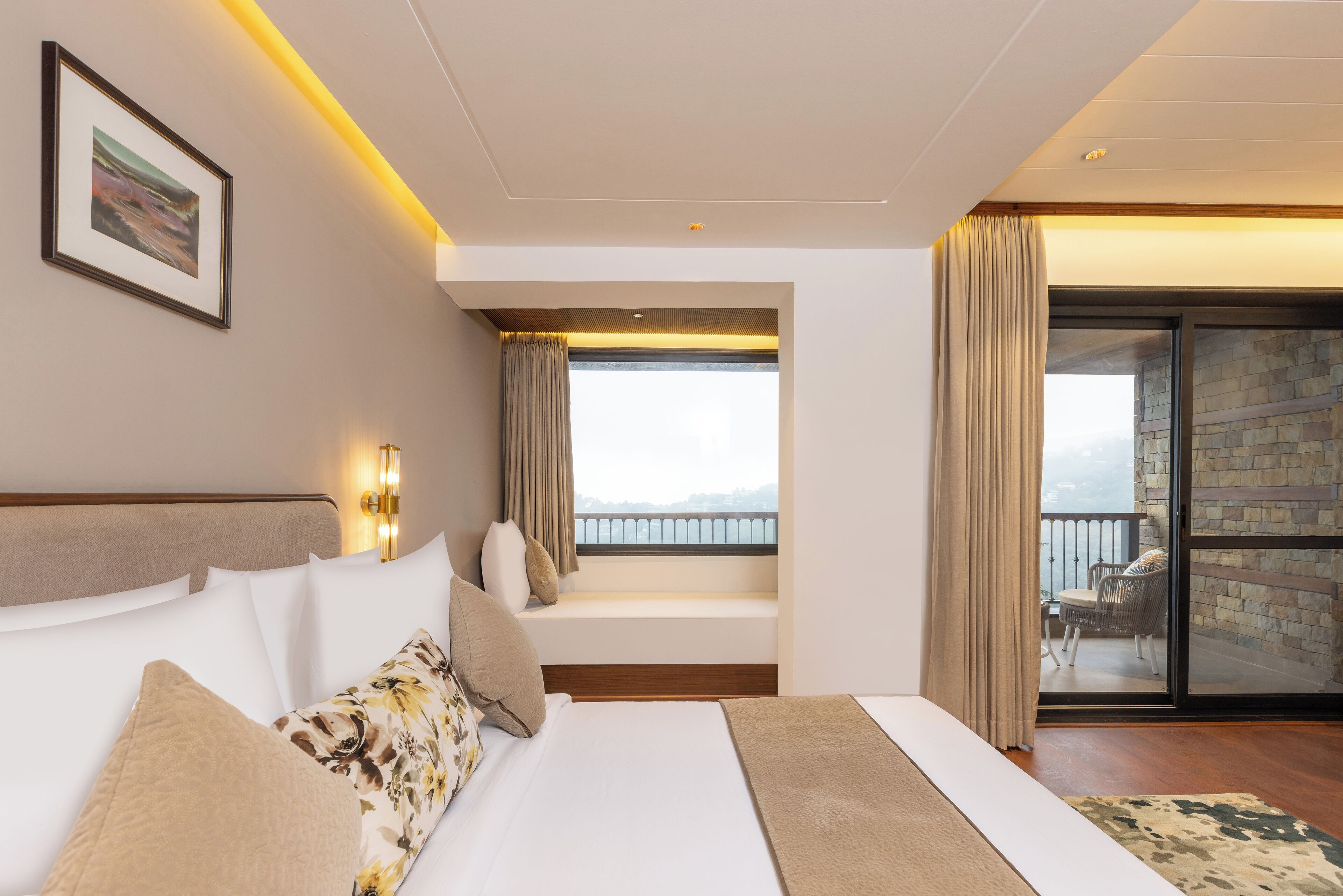 A hotel room with a large bed, a window with a view, and a balcony with a chair.