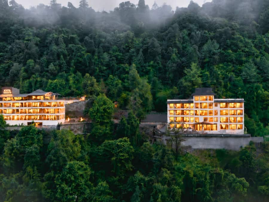 Two multi-story buildings with multiple windows, surrounded by dense forest.