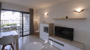 A modern living room with a flat-screen TV, a wooden cabinet, and a dining area with a table and chairs. - Villa Francisca Cambrils (Cambrils)