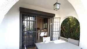 An outdoor patio with a table and chairs, a door with metal bars, and a hanging lantern. - Villa Francisca Cambrils (Cambrils)