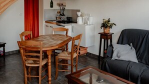 Ein kompakter Wohnraum mit Esstisch, Stühlen, einer Couch, einem Couchtisch, einer Küchenzeile mit Herd, Spüle und Schränken sowie einer Treppe.