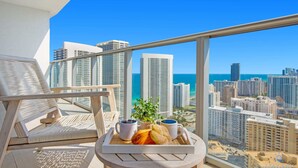 A balcony with a city view, a table with a tray of pastries and coffee cups, and a potted plant. - Luxury Condo | Stunning View | Resort Amenities (Hollywood)