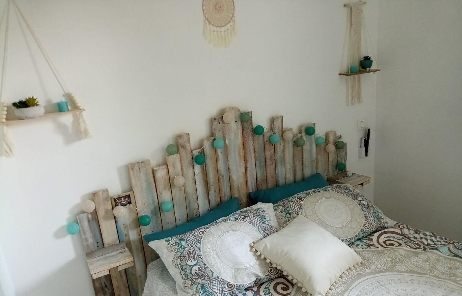 Un dormitorio con cabecera de madera, ropa de cama estampada y pequeños adornos en estanterías.