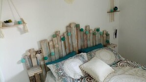 A bedroom with a wooden headboard, patterned bedding, and small decorative items on shelves. - Appartement Village de Vacances (Parentis-en-Born)