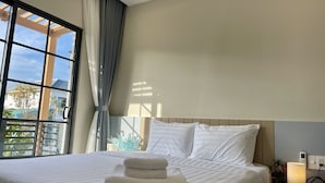 Une chambre d’hôtel avec un lit, une table de chevet avec une lampe et une vue sur l’extérieur par une fenêtre munie de rideaux.