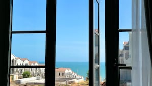 Une vue à travers une fenêtre, avec un ciel dégagé et une côte lointaine.