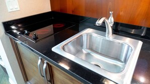 A kitchen with a stainless steel sink, black countertop, and a stove. - MGM Signature | No Resort Fees, Jacuzzi & Pools (Las Vegas)