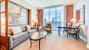 A hotel room with a sofa, armchair, dining table, and chairs. - MGM Signature | No Resort Fees, Jacuzzi & Pools (Las Vegas)
