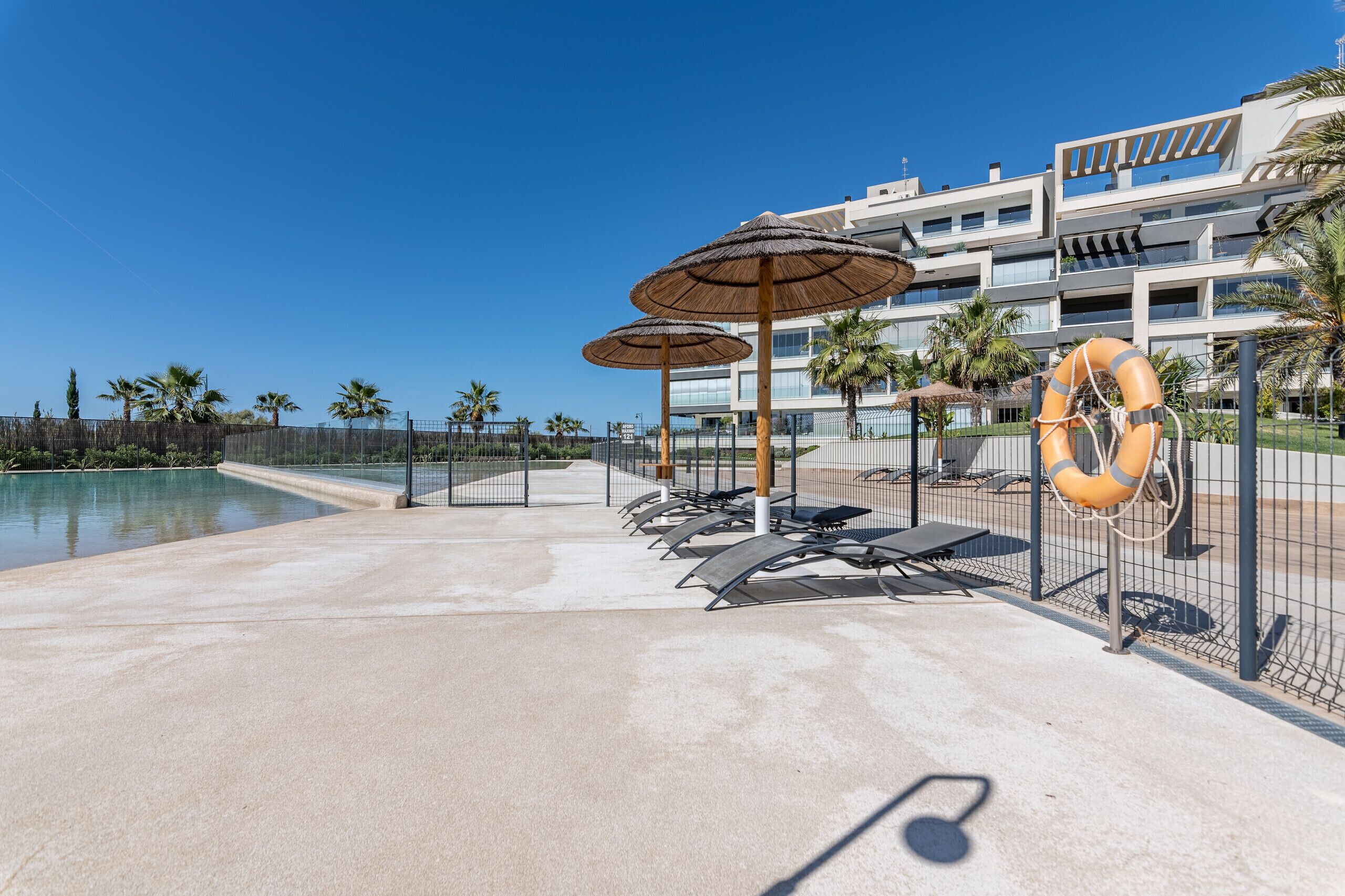 Un espace aménagé au bord de la piscine, avec des chaises longues, des parasols et une bouée de sauvetage.