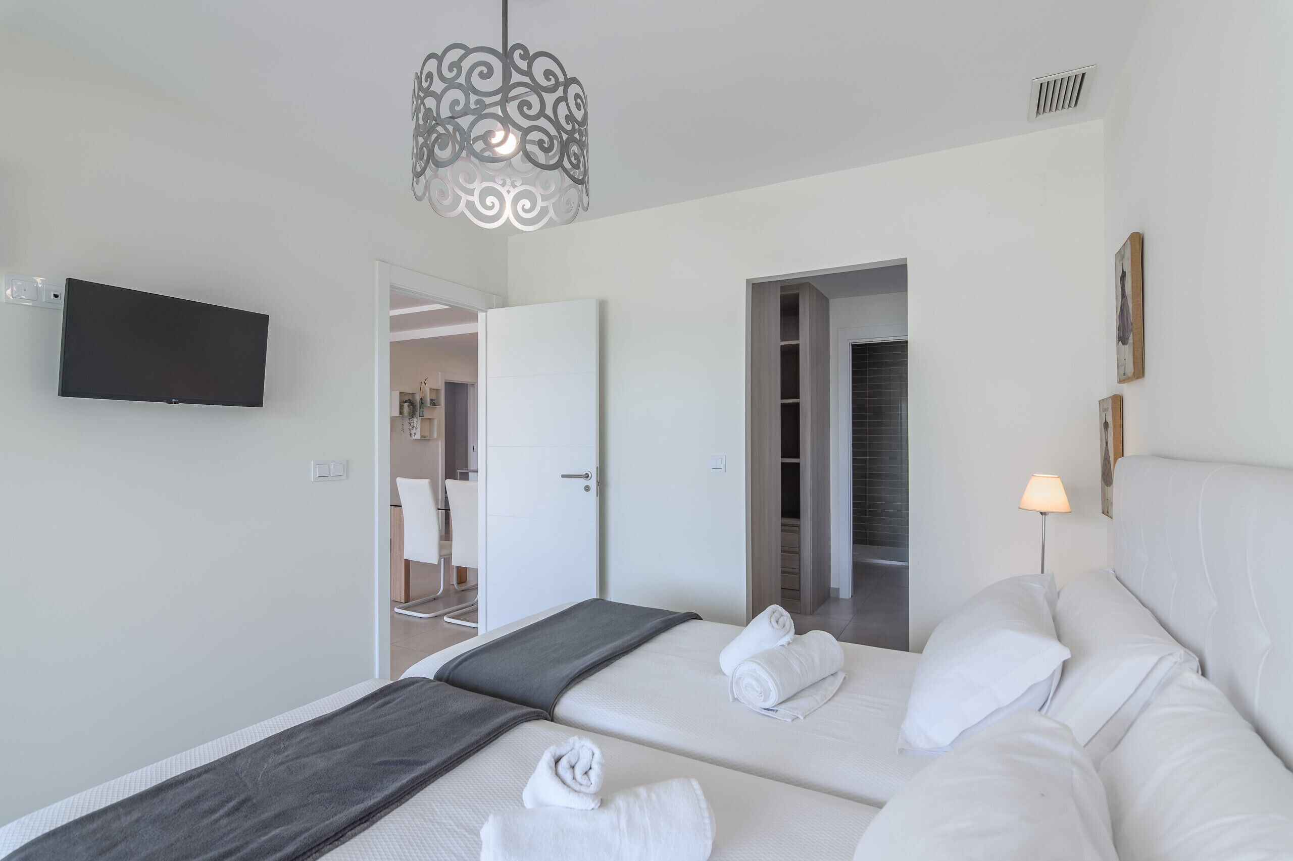 Una habitación de hotel moderna con una cama, mesita de noche, lámpara y televisor montado en la pared.