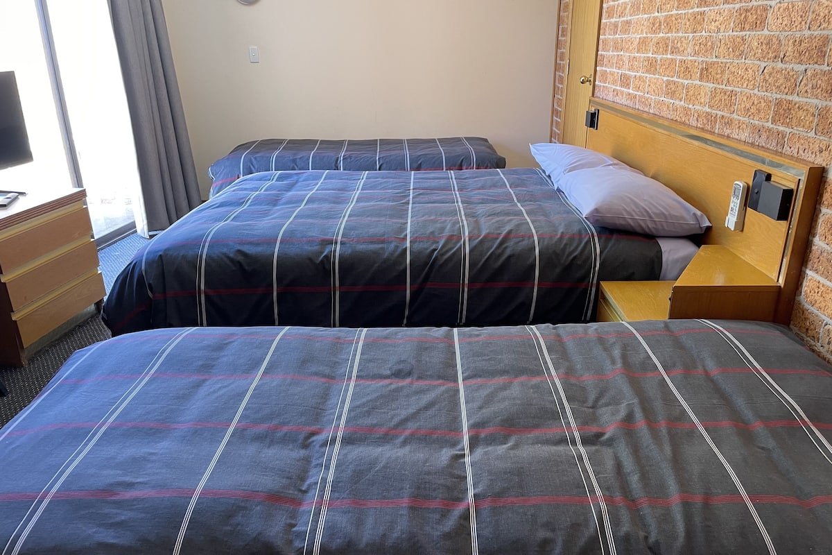 Ein Hotelzimmer mit zwei Betten, einem Holzkopfstück, einem Nachttisch und einem Schminktisch.