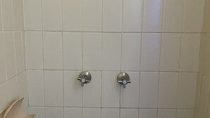 Un baño con azulejos blancos y dos cabezales de ducha.