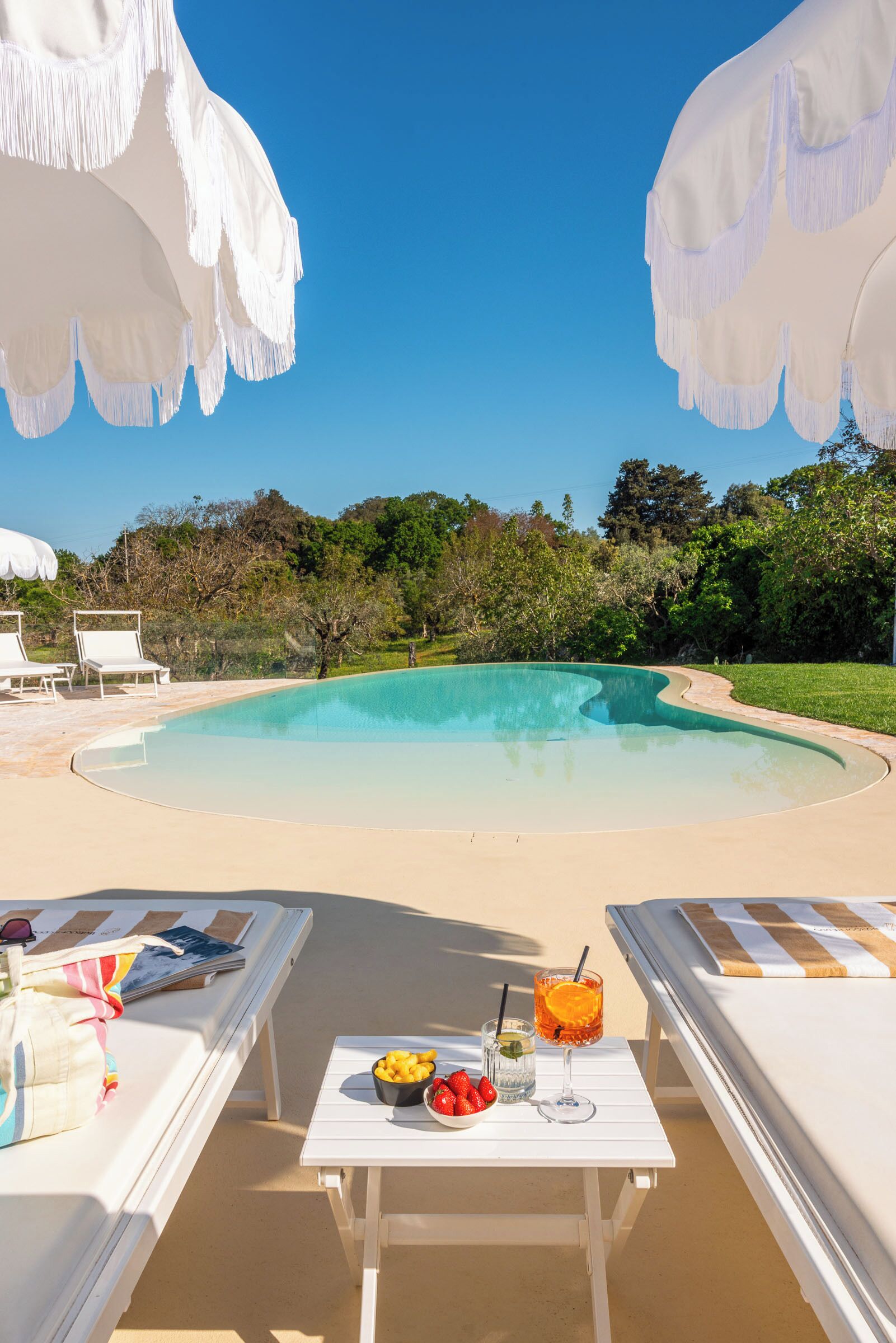 A poolside area with lounge chairs, a table with food and drinks, and a clear view of the pool.