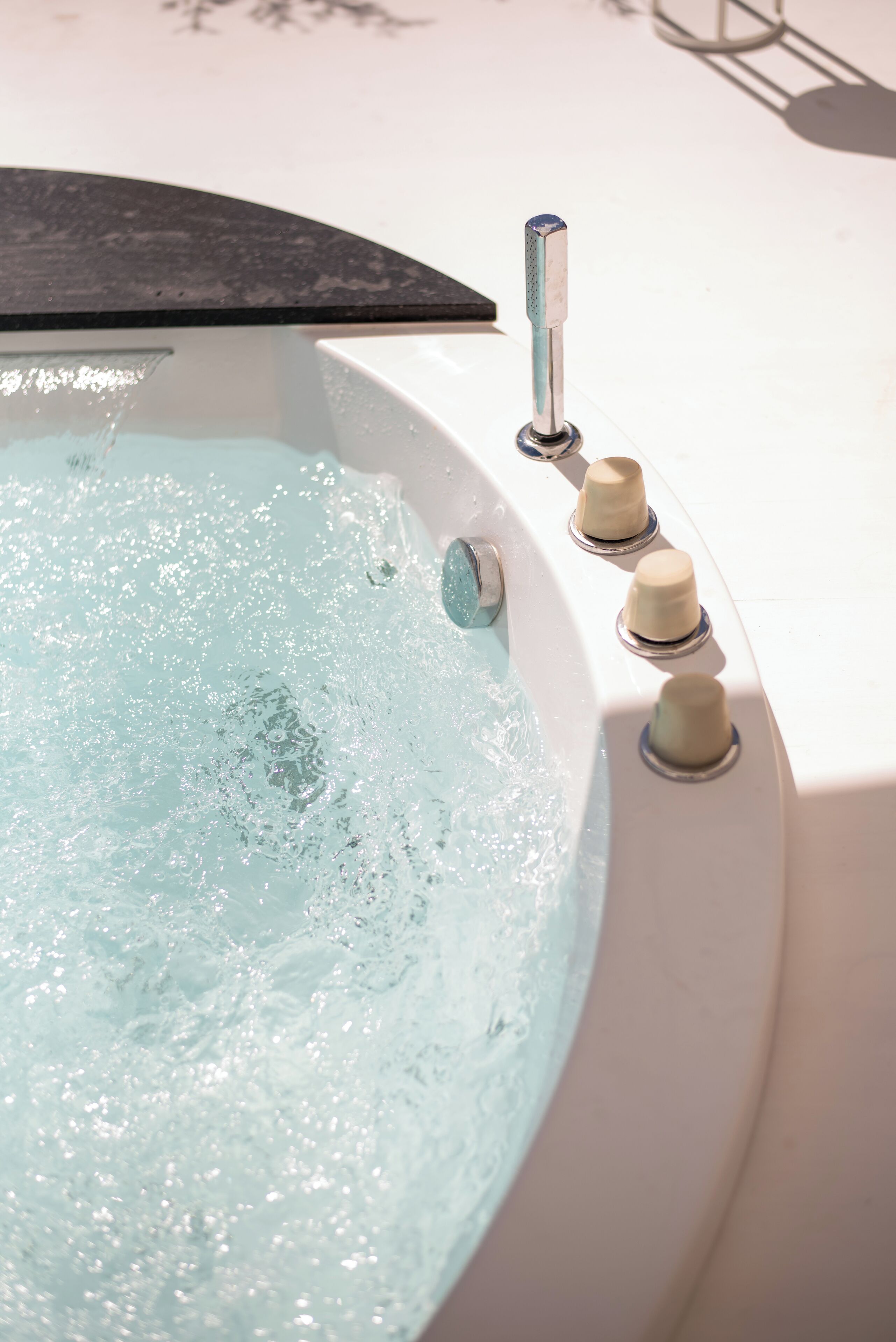 A hot tub with water bubbling, a control panel with knobs, and a black edge.