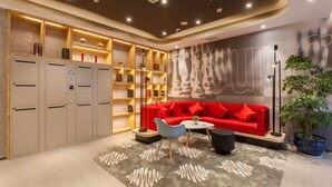 Un espace de détente moderne avec un canapé rouge, une table basse et une bibliothèque.