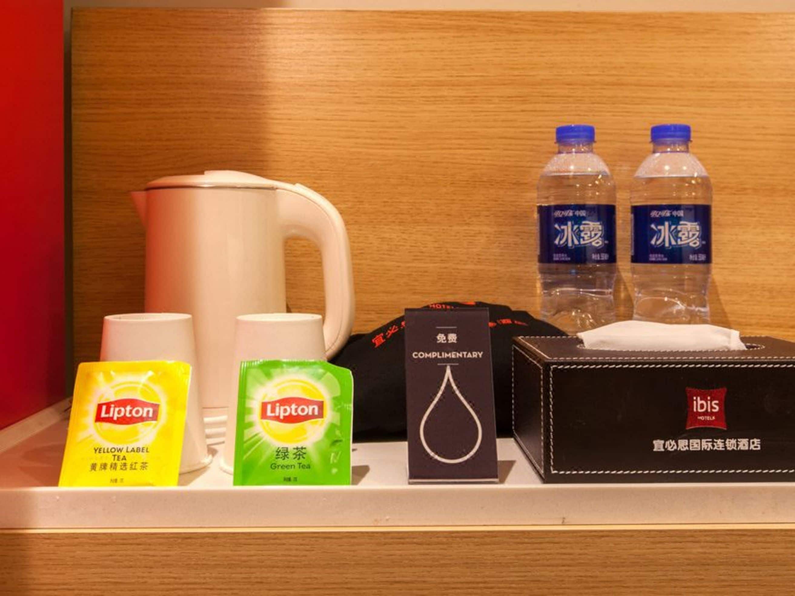 Eine Hotelminibar mit Lipton Tee, Taschentüchern und Wasserflaschen.