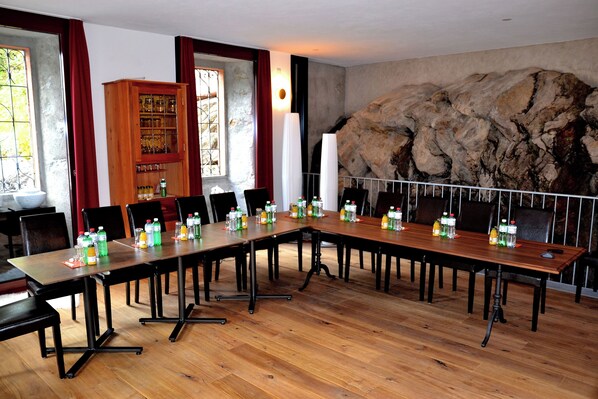 A conference room with a long wooden table, black chairs, and a rock wall.