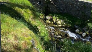 A traditional European-style building with a stone facade, a balcony with red shutters, and a stone bridge over a stream. - Boutique Hotel Fusio (Lavizzara)