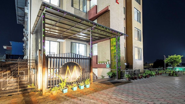 A hotel entrance with a covered walkway, potted plants, and a gated entrance. - Treebo Maurice (Baddi)