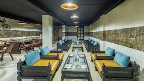 A restaurant with long communal tables, cushioned seating, and pendant lighting. - Treebo Maurice (Baddi)